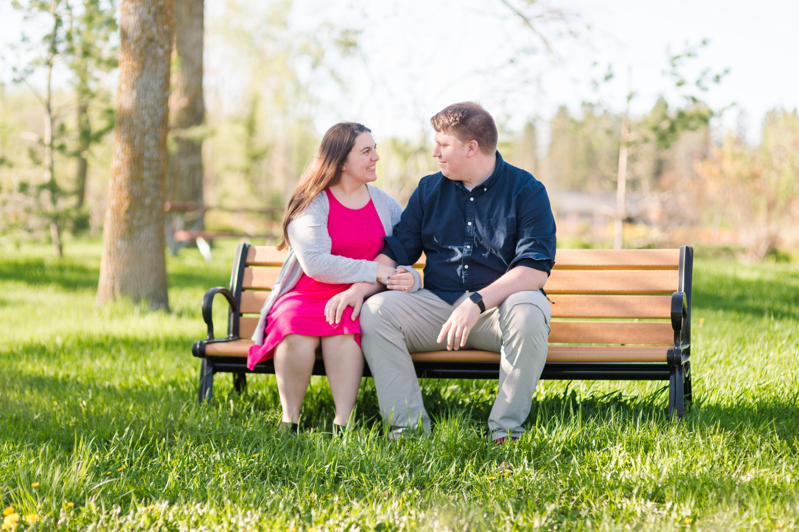 couple on a park bench in the grass at engagement photo session with Chelsy Weisz Photography