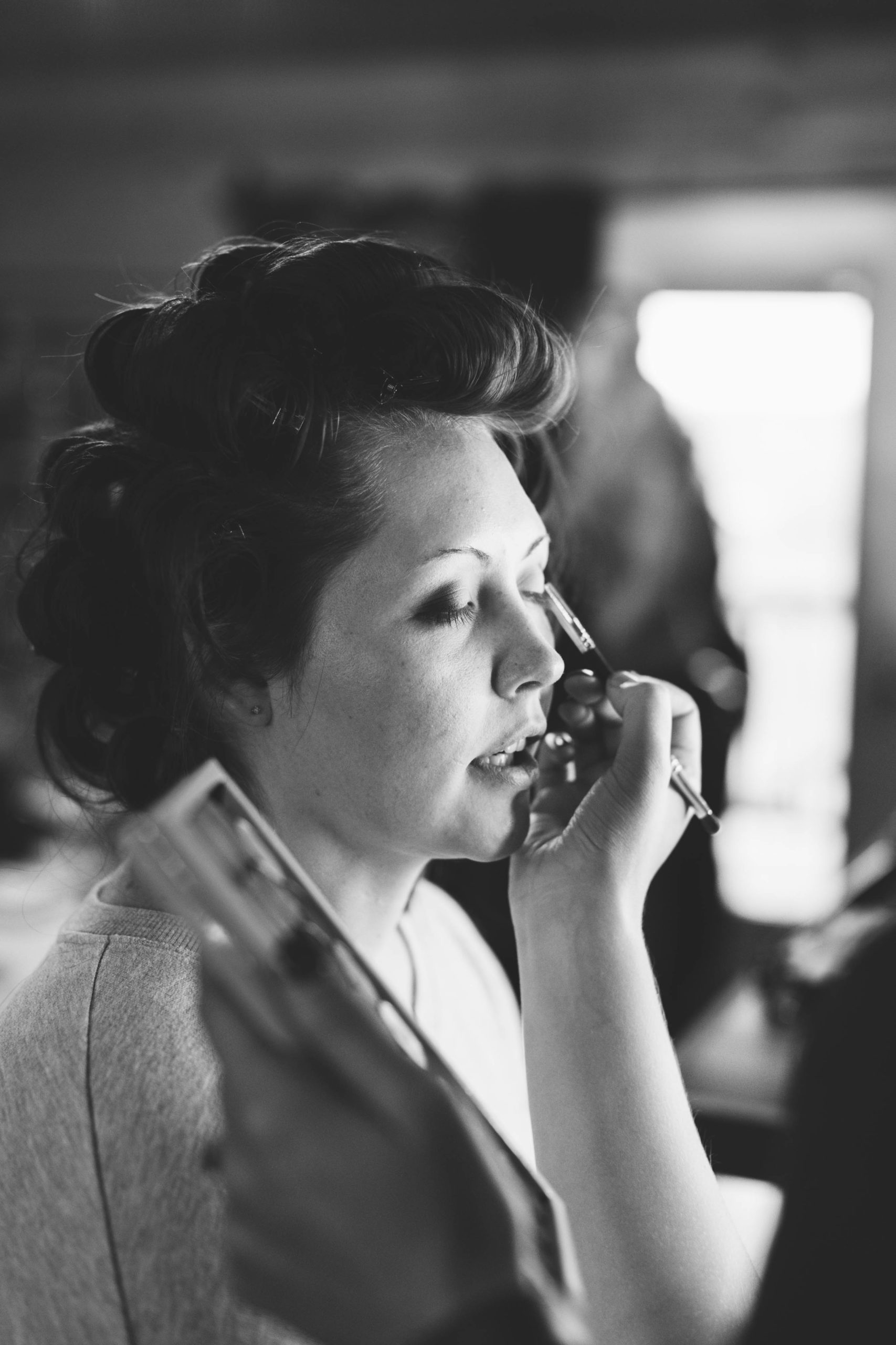 bride getting makeup done on wedding day hair in curlers